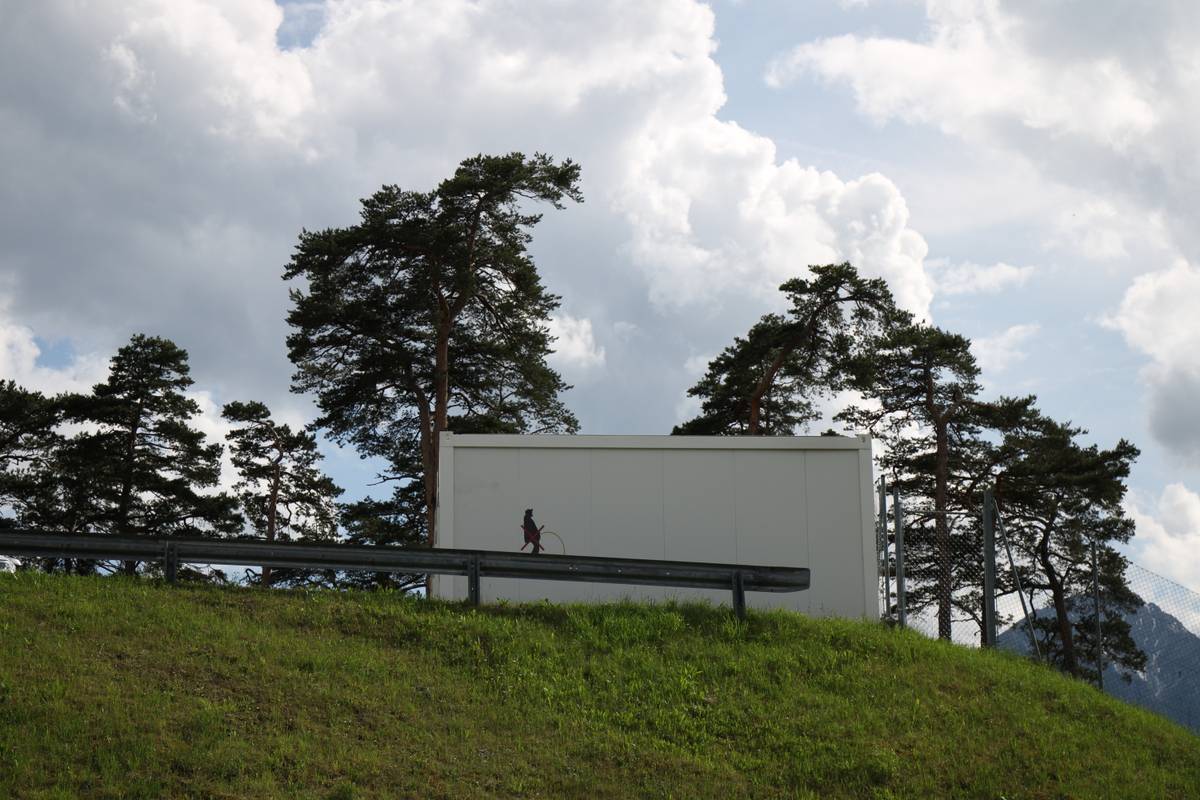 A graphic telling people not to piss off the edge of the hill is spray painted onto a metal building