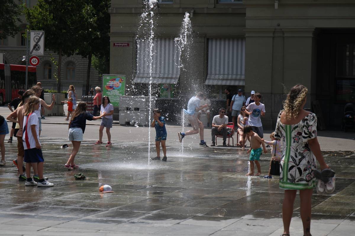 Kids jump through a fountain to cool off on a hot day